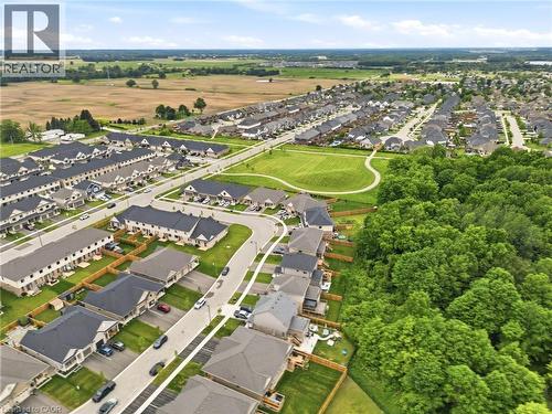 Aerial perspective showcasing a residential community with varied home styles, expansive green spaces, and mature tree lines - 39 Dunning Way, St. Thomas, ON 