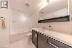 Bathroom featuring a white subway tile shower surround, a white bathtub, and light-toned tile flooring - 