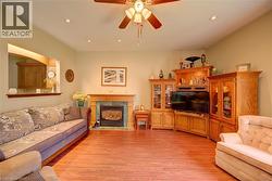Spacious living area featuring wood-finish flooring, a fireplace with a wood mantle and tile surround, and recessed lighting - 