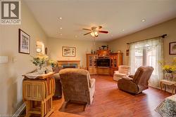 Spacious living area featuring wood-finish flooring, recessed lighting, and a ceiling fan - 