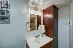 Vanity with integrated sink, mounted mirror, three-light fixture, and adjacent tall storage cabinet - 