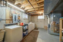 Unfinished basement featuring laundry facilities, exposed ceiling joists, concrete flooring, and a utility sink - 