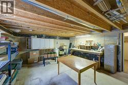 Unfinished basement space featuring exposed wood joists, concrete flooring, built-in cabinetry, and a dedicated workbench area - 