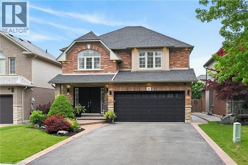 Brick exterior with stone accents, a two-car garage, and a paved driveway with stone border - 43 Wilbur Drive, Binbrook, ON 