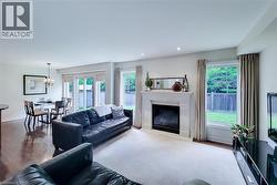 Spacious living area featuring a stone mantel fireplace, bright windows with privacy drapes, and recessed lighting - 