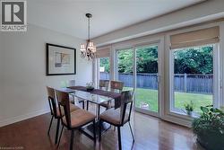 Hardwood flooring complements a chandelier and a sliding glass door leading to a fenced yard - 