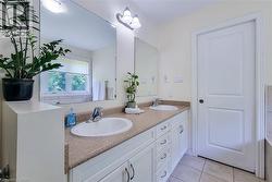 Bathroom featuring a dual-sink vanity with white cabinetry, a speckled countertop, and chrome fixtures - 