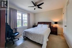 Carpeted room featuring a ceiling fan with integrated lighting, a double-hung window with grid pattern, and neutral wall tones - 