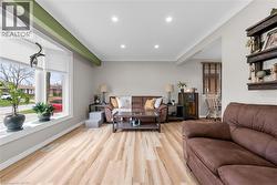 The living area features light-toned flooring, recessed lighting, and a bay window providing natural light - 