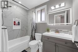 This bathroom features a white bathtub with marble-style tiled walls and a recessed shelf, alongside a toilet - 