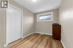 This room features light-colored walls, wide plank flooring, and a window with white trim - 