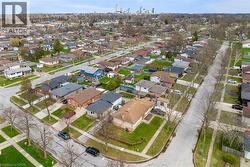 Aerial view of the neighborhood showcasing tree-lined streets, residential properties with green lawns, and a distant city skyline - 