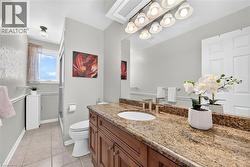 Bathroom featuring a dual-sink vanity with a granite countertop, wood-finish cabinetry, and brushed nickel fixtures - 