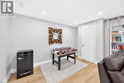 Finished room featuring light wood-finish flooring, recessed lighting, a built-in white bookshelf, and light gray wall paint - 