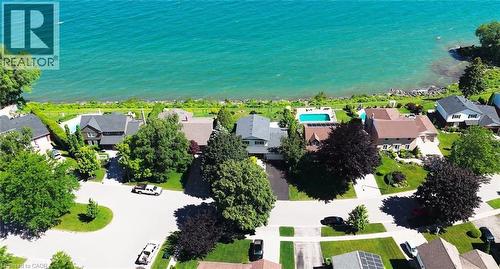 Waterfront property featuring a private swimming pool, expansive green lawn, mature trees, and a paved driveway - 15 Cheval Drive, Grimsby, ON - Outdoor With Body Of Water With View