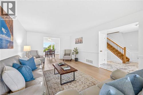 Bright living area featuring wood-finish flooring and white walls with wainscoting - 15 Cheval Drive, Grimsby, ON - Indoor Photo Showing Living Room