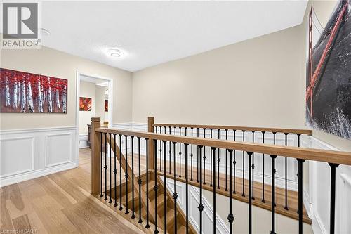 Upper-level hallway featuring wood-finish flooring, wainscoting, and a staircase with wood handrails and black metal balusters - 15 Cheval Drive, Grimsby, ON - Indoor Photo Showing Other Room