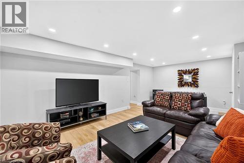 Recessed lighting illuminates this room featuring light wood-finish flooring, white walls, and a built-in media console - 15 Cheval Drive, Grimsby, ON - Indoor
