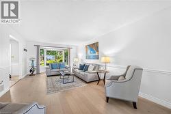 Bright living area featuring wood-finish flooring, white wainscoting, and a large bay window - 