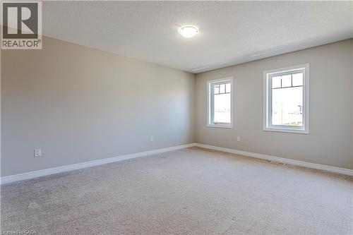 Spacious room featuring neutral carpeting, light-toned wall paint, crisp white trim, and two bright windows with white frames - 3896 Tufgar Crescent, Burlington, ON 