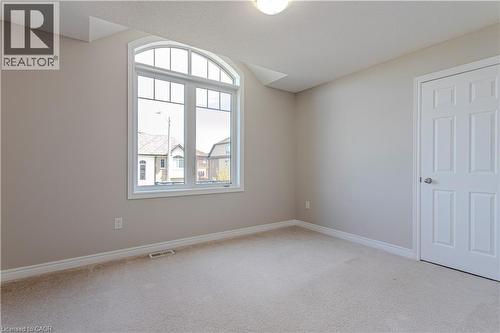 Room featuring a large arched window, neutral wall paint, white trim, and light-colored carpeting - 3896 Tufgar Crescent, Burlington, ON 