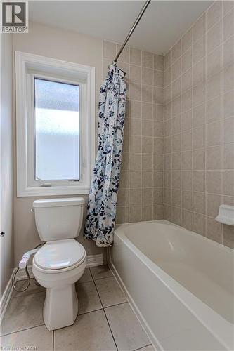Bathroom featuring a white bathtub, ceramic wall tiling, and a window with frosted glass - 3896 Tufgar Crescent, Burlington, ON 