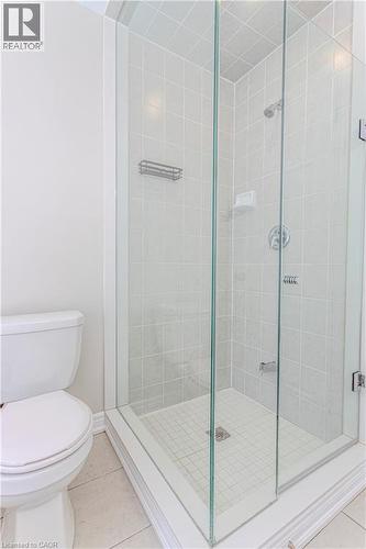 Glass-enclosed shower featuring white square tile walls, a small square tile floor, and chrome fixtures - 3896 Tufgar Crescent, Burlington, ON 