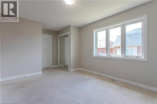 Spacious room featuring neutral paint, light-colored carpeting, a large three-pane window, and a mirrored closet - 3896 Tufgar Crescent, Burlington, ON 
