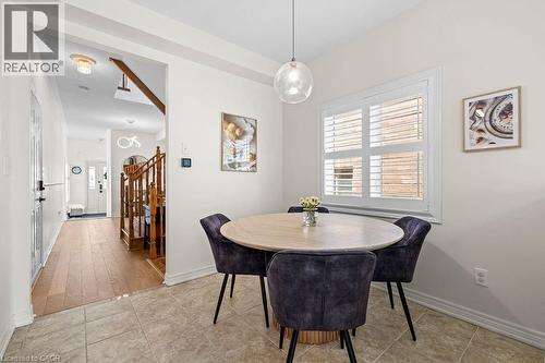 Dining area featuring tile flooring, a clear glass pendant light fixture, and a window with white louvered shutters - 4670 Thomas Alton Boulevard, Burlington, ON 