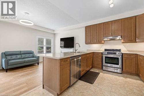 Open-concept kitchen featuring light wood-finish cabinetry, stainless steel appliances, a center island with a sink, and a light-toned countertop - 4670 Thomas Alton Boulevard, Burlington, ON 