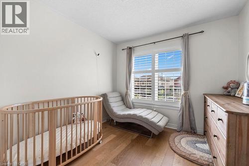 Bright room featuring wood-finish flooring, white walls, and a large window with white louvered blinds - 4670 Thomas Alton Boulevard, Burlington, ON 