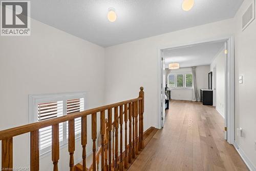 Upper hallway featuring wood-finish flooring and a wood baluster railing - 4670 Thomas Alton Boulevard, Burlington, ON 