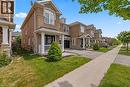 Brick and stone facade townhome featuring a covered porch with white columns and railing - 4670 Thomas Alton Boulevard, Burlington, ON 
