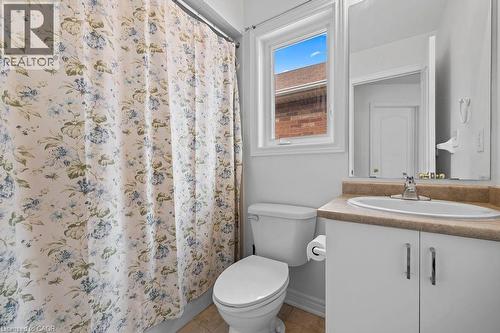 Compact bathroom featuring a window, white vanity with integrated sink, coordinating countertop, and a wall-mounted mirror - 4670 Thomas Alton Boulevard, Burlington, ON 