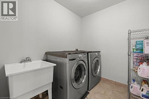 Dedicated laundry area featuring a utility sink, tile flooring, and ample wall space - 4670 Thomas Alton Boulevard, Burlington, ON 
