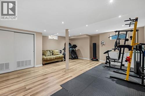 Finished basement area featuring recessed lighting, wood-finish flooring, a support column, and a sliding closet door - 4670 Thomas Alton Boulevard, Burlington, ON 