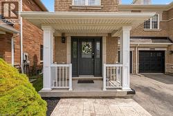 Covered front porch with white columns and railings, featuring a dark gray door with decorative glass inserts - 