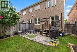 Expansive rear yard featuring a paved patio area, wood deck with stairs, privacy fencing, and a raised garden bed - 