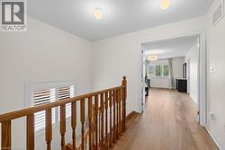 Upper hallway featuring wood-finish flooring and a wood baluster railing - 