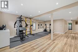 Spacious lower-level room featuring light wood-finish flooring, recessed lighting, and neutral wall tones - 