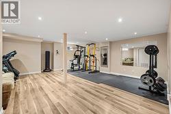 Spacious recreational room featuring wood-finish flooring, recessed lighting, and a neutral color palette - 