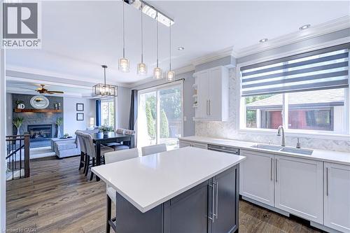 Open-concept kitchen featuring a large island with white countertop, white shaker-style cabinetry, and herringbone tile backsplash - 1406 Marshall Crescent, Milton, ON 