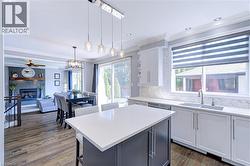 Open-concept kitchen featuring a large island with white countertop, white shaker-style cabinetry, and herringbone tile backsplash - 