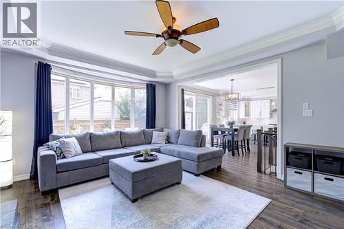 Living area featuring wood-finish flooring, a tray ceiling with crown molding, and a ceiling fan - 1406 Marshall Crescent, Milton, ON 