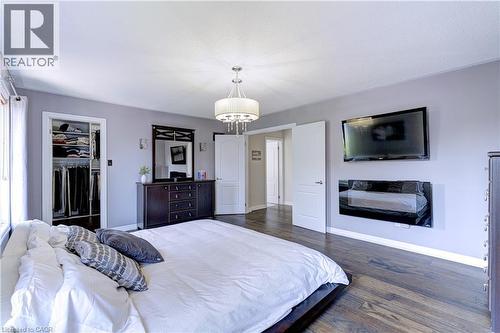 Spacious room featuring wood-finish flooring, a contemporary chandelier, and a built-in closet with shelving and hanging rods - 1406 Marshall Crescent, Milton, ON 