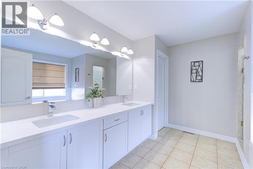Double vanity with white cabinetry, integrated sinks, chrome faucets, and an expansive mirror - 1406 Marshall Crescent, Milton, ON 