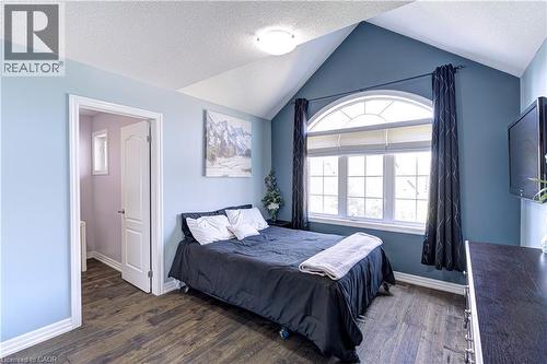 Vaulted ceiling bedroom featuring a large arched window with horizontal blinds and dark drapery - 1406 Marshall Crescent, Milton, ON 