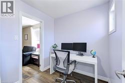 Interior room with wood-finish flooring, light-toned walls, and a white baseboard trim - 