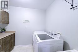 Laundry area with wood-finish cabinetry, light-toned countertop, and tile flooring - 