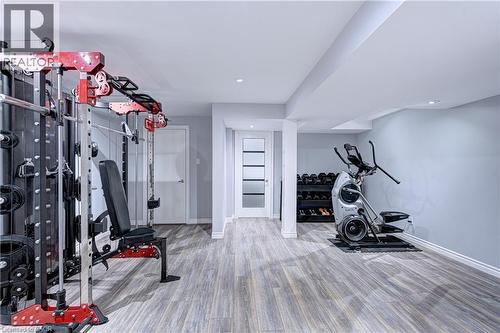 Spacious room featuring wood-finish flooring, recessed lighting, light gray wall paint, and a modern interior door with frosted glass panels - 1406 Marshall Crescent, Milton, ON 